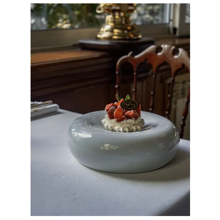 Dessert Zeffirino con fragole fresche, panna montata e targhetta logata su piatto elegante