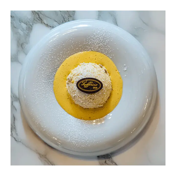 Dessert Zeffirino servito su crema gialla con targhetta in cioccolato e zucchero a velo